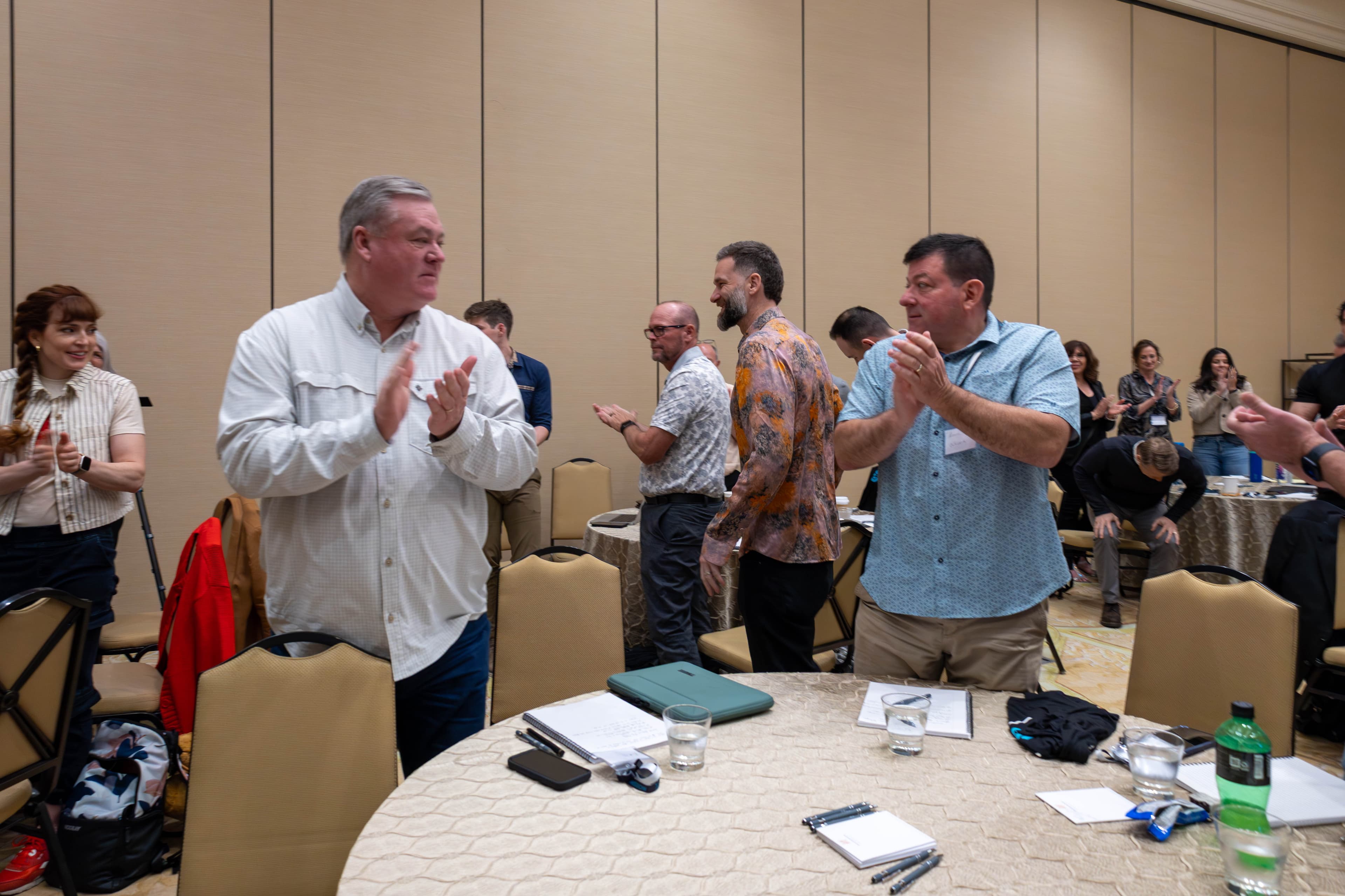 Attendees applauding at tables